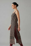 Side view of sleeveless black printed strappy slip kurta showing long straight cut and high side slit over leggings.