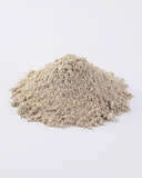Close-up of loose Multani mitti and rose face pack powder piled on a white surface