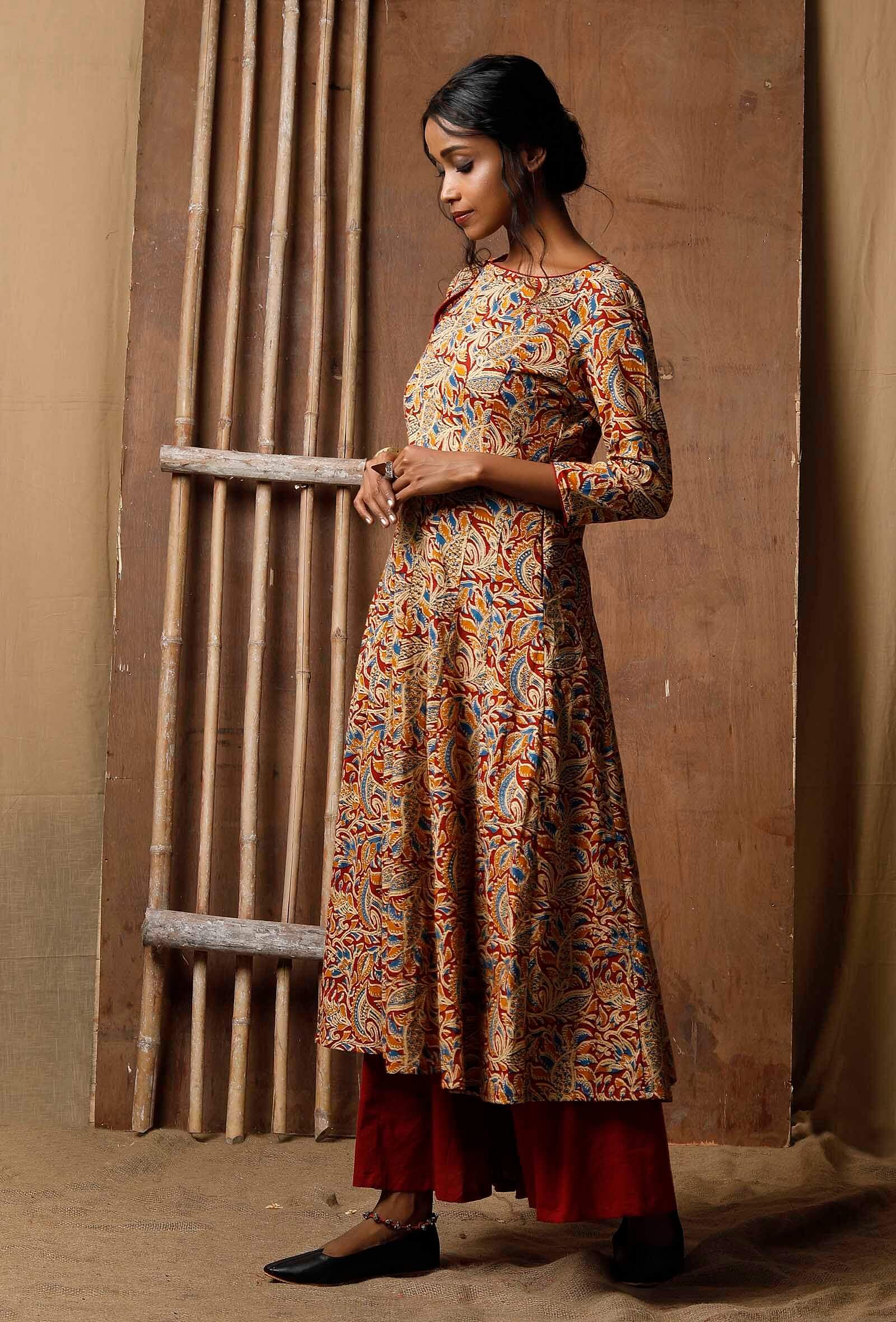 Side view of handcrafted Kalamkari cotton kurta in red, blue and mustard print, styled with red palazzo pants